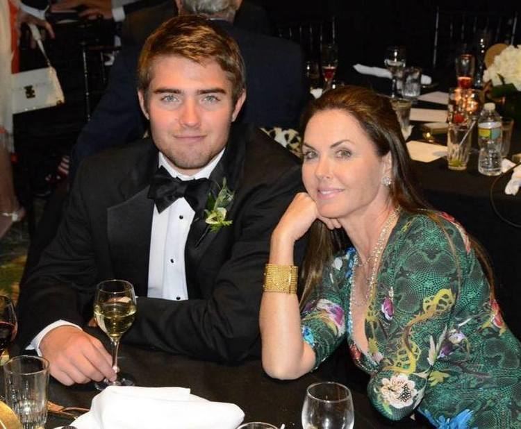 Bridget Rooney Koch smiling in a green dress and sitting beside  his son Liam Rooney Koch in a black suit