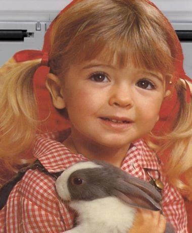 Bridgette Andersen smiling while holding a rabbit and wearing a red checkered blouse