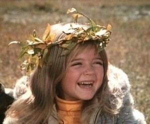 Bridgette Andersen smiling while wearing a flower crown and beige jacket