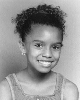 Brooke Marie Bridges smiling in a ponytail and wearing a sleeveless blouse and round earrings