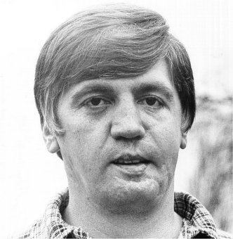 Buford Pusser is serious, has black hair, his mouth half opened, and wears black checkered polo.