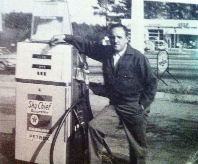 C. P. Ellis standing beside a gasoline station.