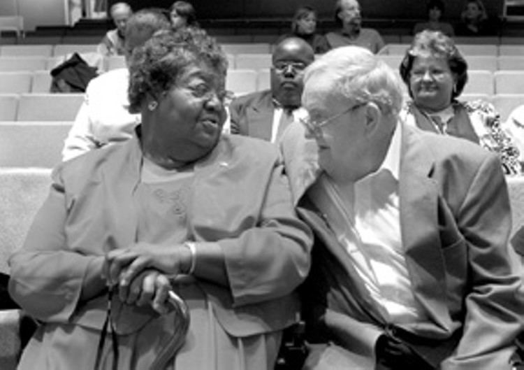 C. P. Ellis wearing a suit while looking at Ann Atwater holding a cane.