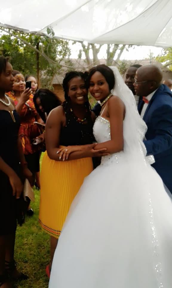 Bathabetsoe Diana Nare Mathema smiling with the woman beside her while she is wearing a wedding gown, veil, necklace, and ring