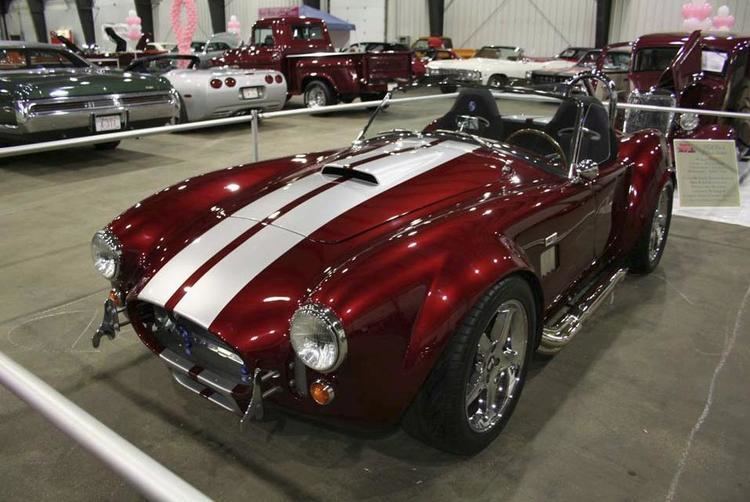 AC Shelby Cobra in a candy apple red color with two white stripes on the hood