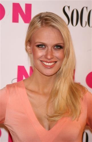 CariDee English smiling with blonde hair while wearing a peach blouse with a plunging neckline