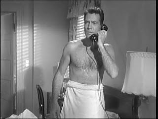 Carl Betz talking with someone over the telephone with a towel wrap around his waist