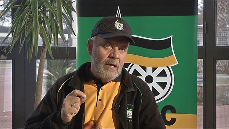 Carl Niehaus wearing black cap, black jacket and yellow polo shirt