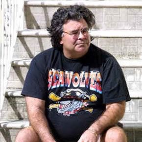 Carlos Lehder wearing black printed t-shirt and eyeglasses while sitting on the stairs