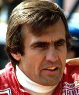 Carlos Reutemann looking afar and wearing a red racing suit