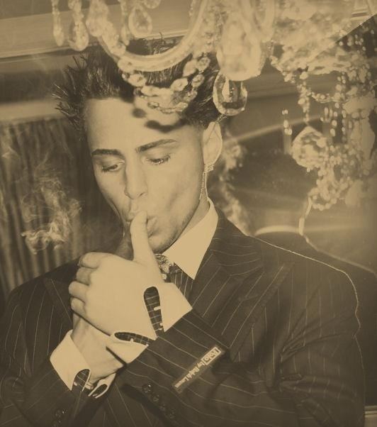 Young Carmine Agnello wearing black striped coat and white long sleeves while smoking