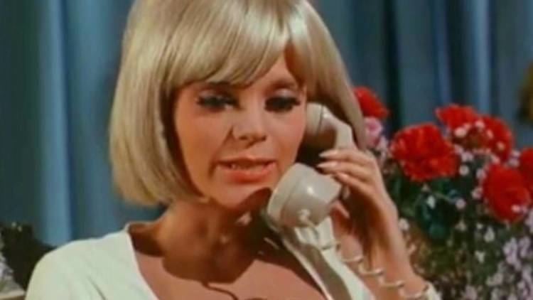Carol Wayne talking with someone over the phone while wearing a white blouse