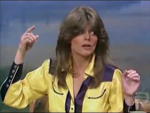 Carol Wayne raising her hands while wearing a yellow and dark blue long sleeves