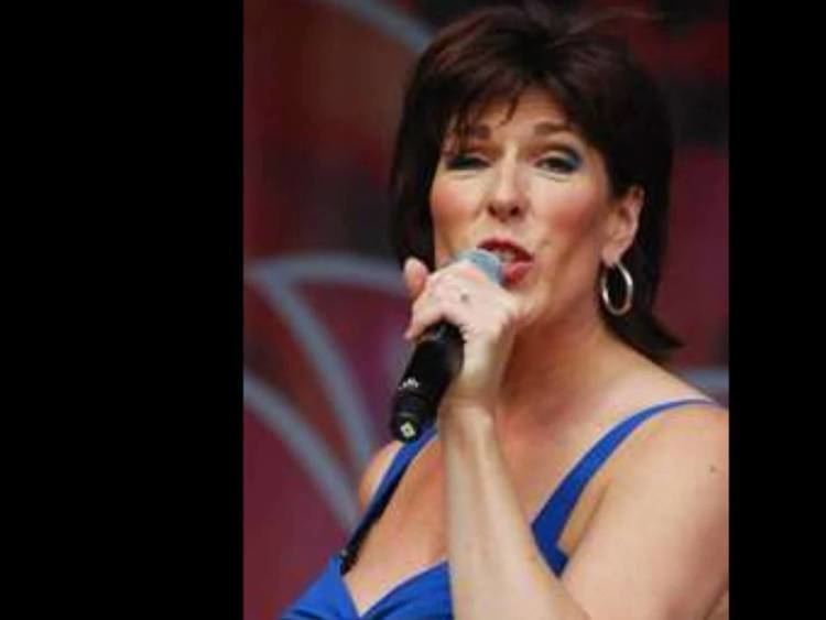 Carola Smit while singing wearing a blue sleeveless shirt