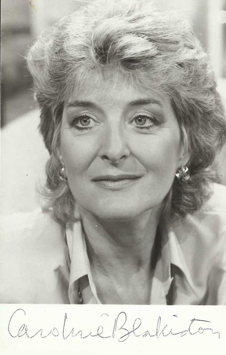 Caroline Blakiston smiling and looking afar with short wavy hair and her name at the bottom of the portrait while she is wearing earrings and a blouse
