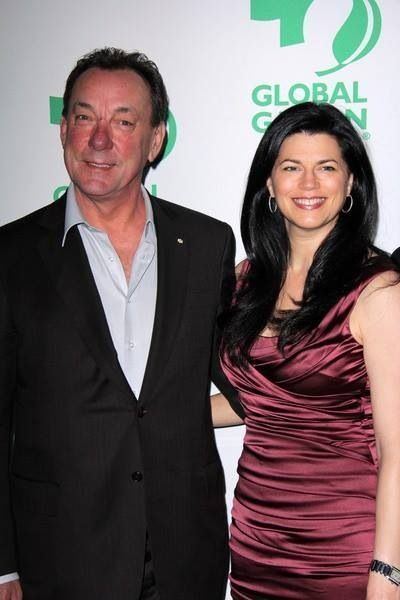 Carrie Nuttall smiling and wearing a ruched silk dress and earrings while Neil Peart wearing a black coat and white long sleeves