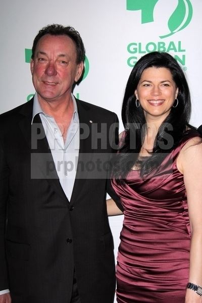 Carrie Nuttall smiling and wearing a ruched silk dress and earrings while Neil Peart wearing a black coat and white long sleeves