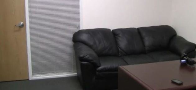 Color black casting couch and a brown table with a cellphone on the top.
