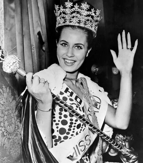 Catharina Lodders smiling while waving her hand and wearing the crown, sash, and polka dot dress