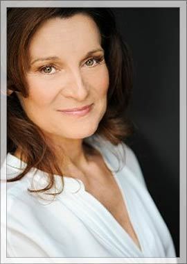 Catherine McGoohan with a tight-lipped smile while wearing a white blouse