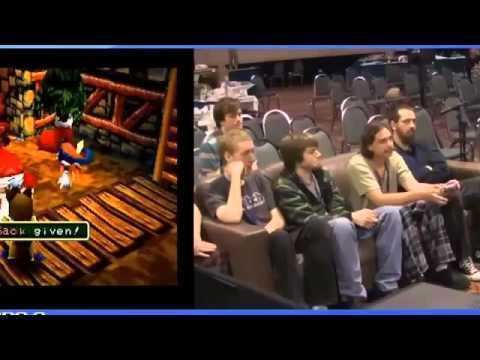 On the left, Tomba 2 game. On the right, Caveman DCJ sitting on a couch with Chibi and other players. Caveman DCJ wearing a light green shirt and checkered black and white pants.