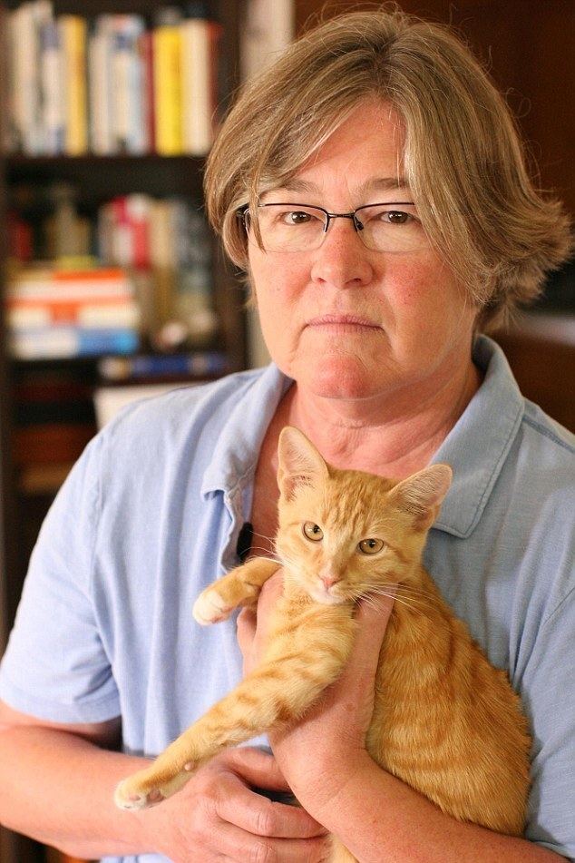 Tracey Tarlton holding a cat while wearing a light blue polo shirt and eyeglasses