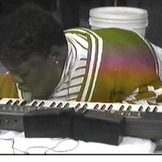 Celestine Tate Harrington playing the keyboard with her tongue while wearing a brown and white striped blouse