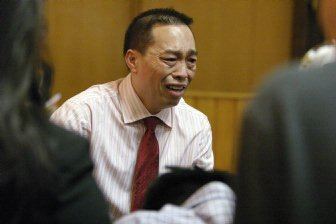 Chai Vang talking with a sad facial expression at court and wearing a long-sleeved striped formal shirt and a red tie.