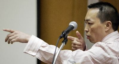 Chai Vang talking at court during a trial and wearing a long-sleeved striped formal shirt.