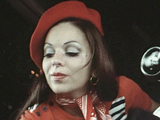 Chantal Contouri looking below with her black hair and wearing an earring, a red hat, a red scarf around her neck, and a red dress