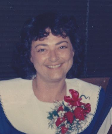 Charlene Corley smiling while wearing a white and blue dress with flowers on the side