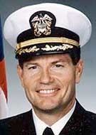 Charles Burlingame smiling while wearing a white shirt under a blue suit and a navy hat
