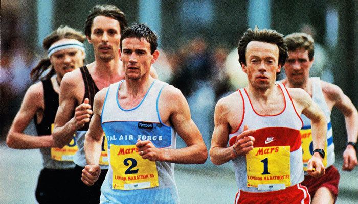 Charlie Spedding running on a red and white shirt numbered one along with other participants during the 1985 London Marathon