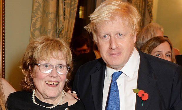Charlotte Johnson Wahl smiling while wearing a black dress, necklace, and eyeglasses while Boris Johnson wearing a coat, long sleeves, and necktie