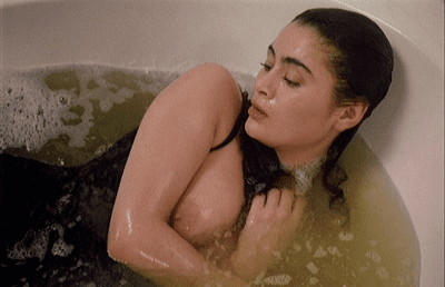 Charlotte Lewis inside a bathtub showing her breast in a movie scene from Minnacia d'Amore (a 1988 film).
