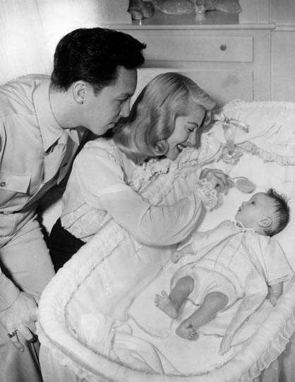 Lana Turner and Stephen Crane smiling while looking at Cheryl Crane