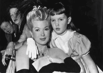 Lana Turner smiling and wearing a black dress and Cheryl Crane wearing a puff sleeve dress