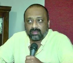 Chetan wearing yellow polo shirt while holding a microphone