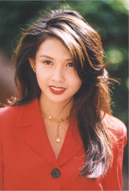 Chingmy Yau smiling while wearing a red long sleeve, gold necklace, and earrings