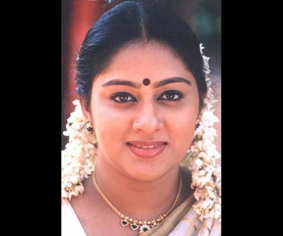 Chippy smiling with a Bindi on her forehead and white flowers in her hair while wearing a white dress.