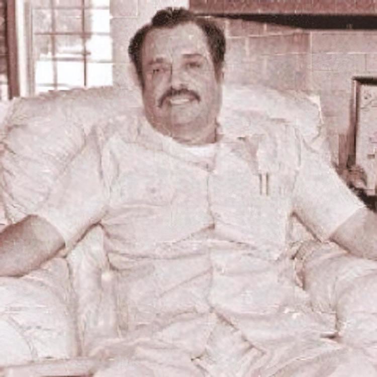 Rodrigo Ángel "Chito" Cano Rodríguez with a mustache and sitting on a couch.
