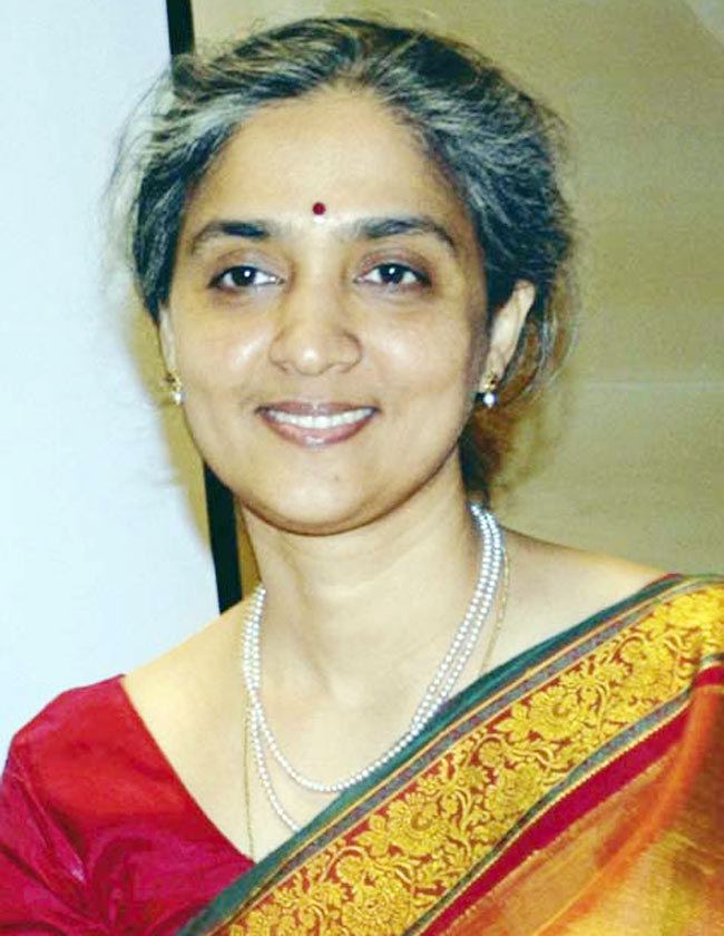 Chitra Ramkrishna smiling, wearing earrings, a necklace, and a multi-colored traditional Indian dress called Saree.