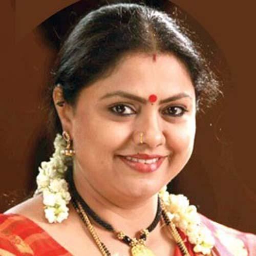 Chitra Shenoy smiling with a nose pierce and a red mark on her forehead while wearing a red saree and necklaces