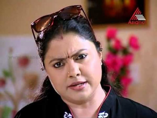 Chitra Shenoy speaking with furrowed eyebrows while wearing a black blouse and shades on her head