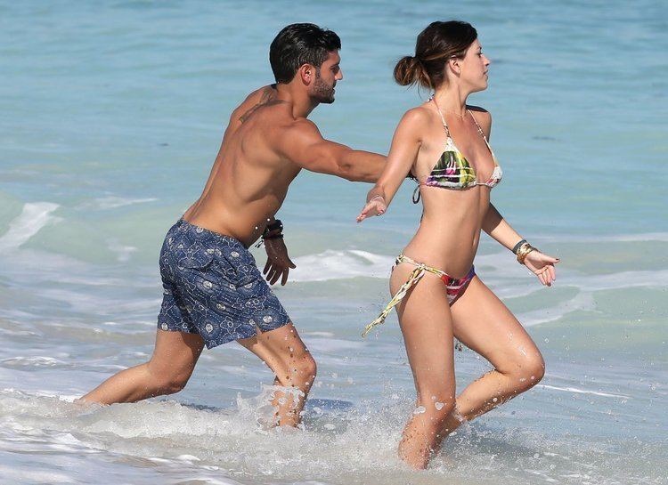 Chloe Melas enjoying the beach and wearing a black and yellow bikini while Brian Mazza wearing blue shorts