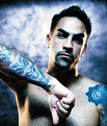 Chris Núñez' serious face while showing his arm's tattoos