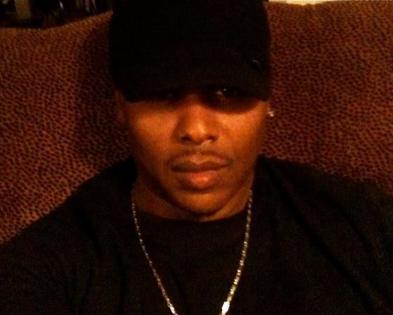 Christian Payton wearing a black cap, necklace, and black t-shirt