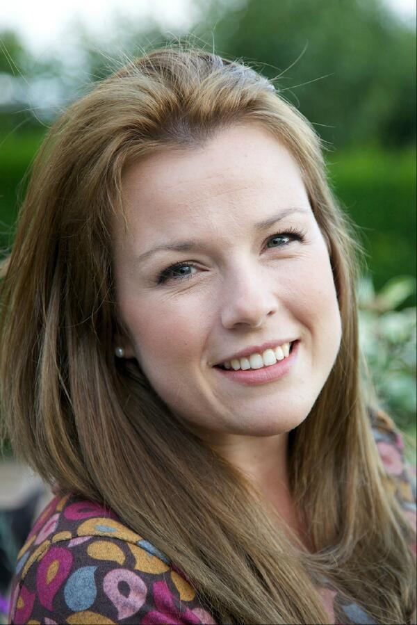 Christina Trevanion smiling with blonde hair down and wearing a colored blouse and pearl earrings