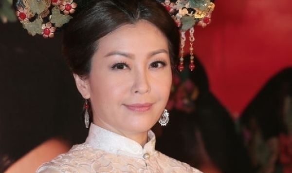 Christine Ng with a smiling face, wearing a headdress and earrings.