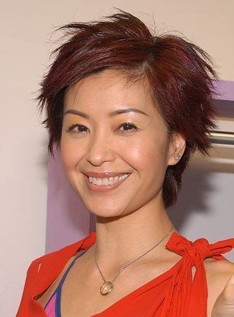 Christine Ng smiling, with short hair and wearing an orange top.